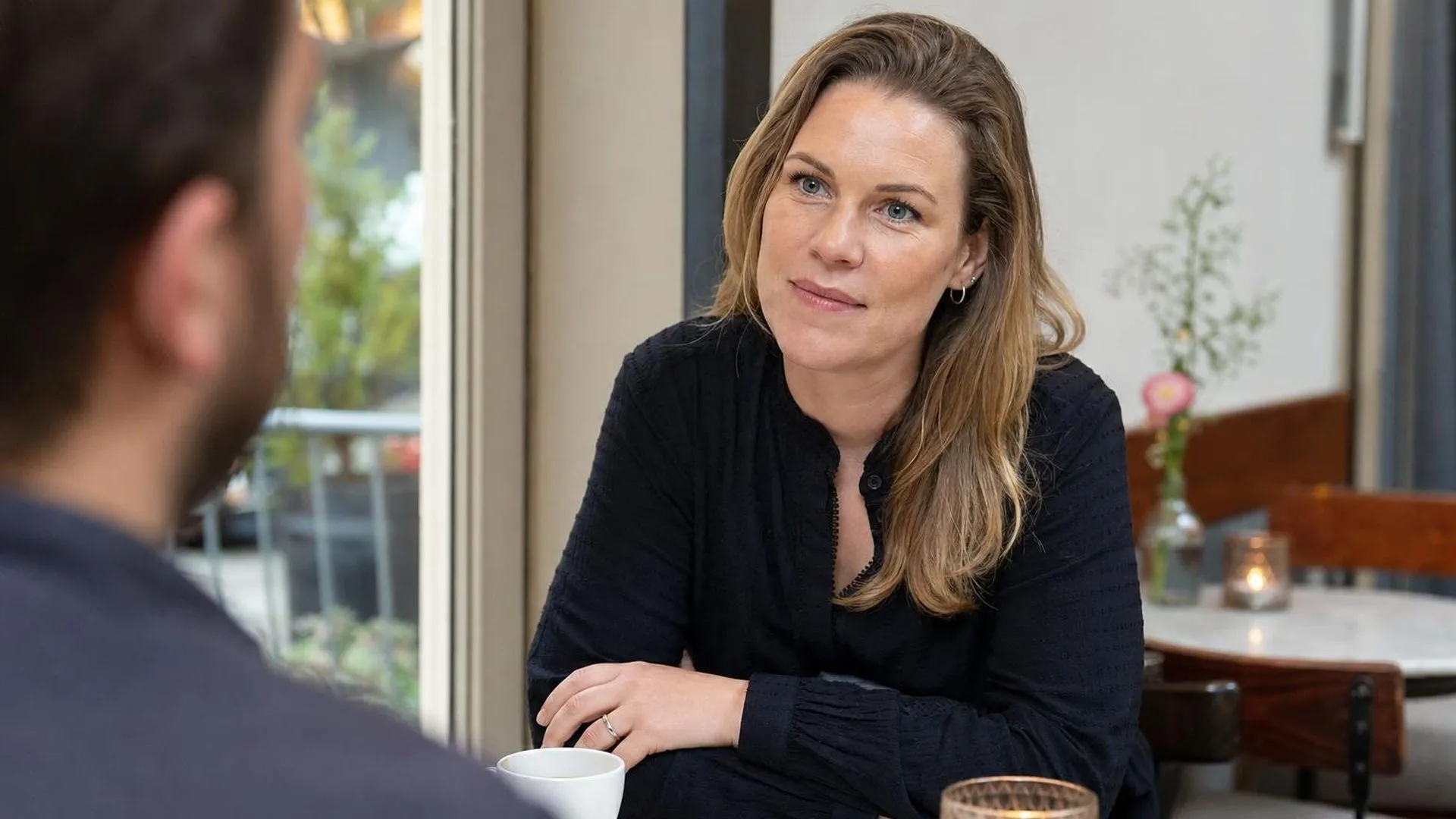 Twee mensen in gesprek aan een cafétafel, één luistert aandachtig