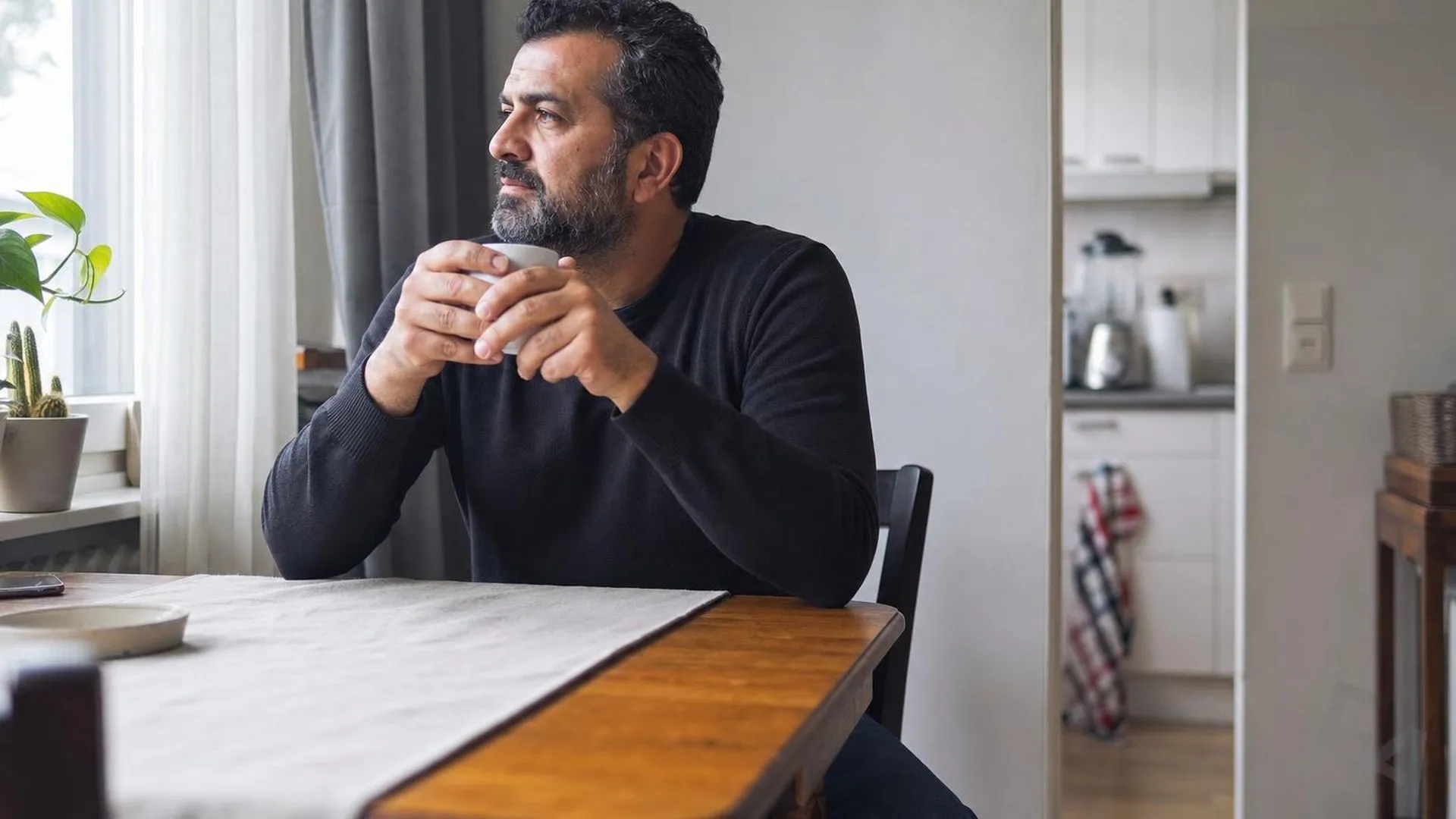 Alleenstaande ouder zit uitgeput aan de keukentafel in de ochtend