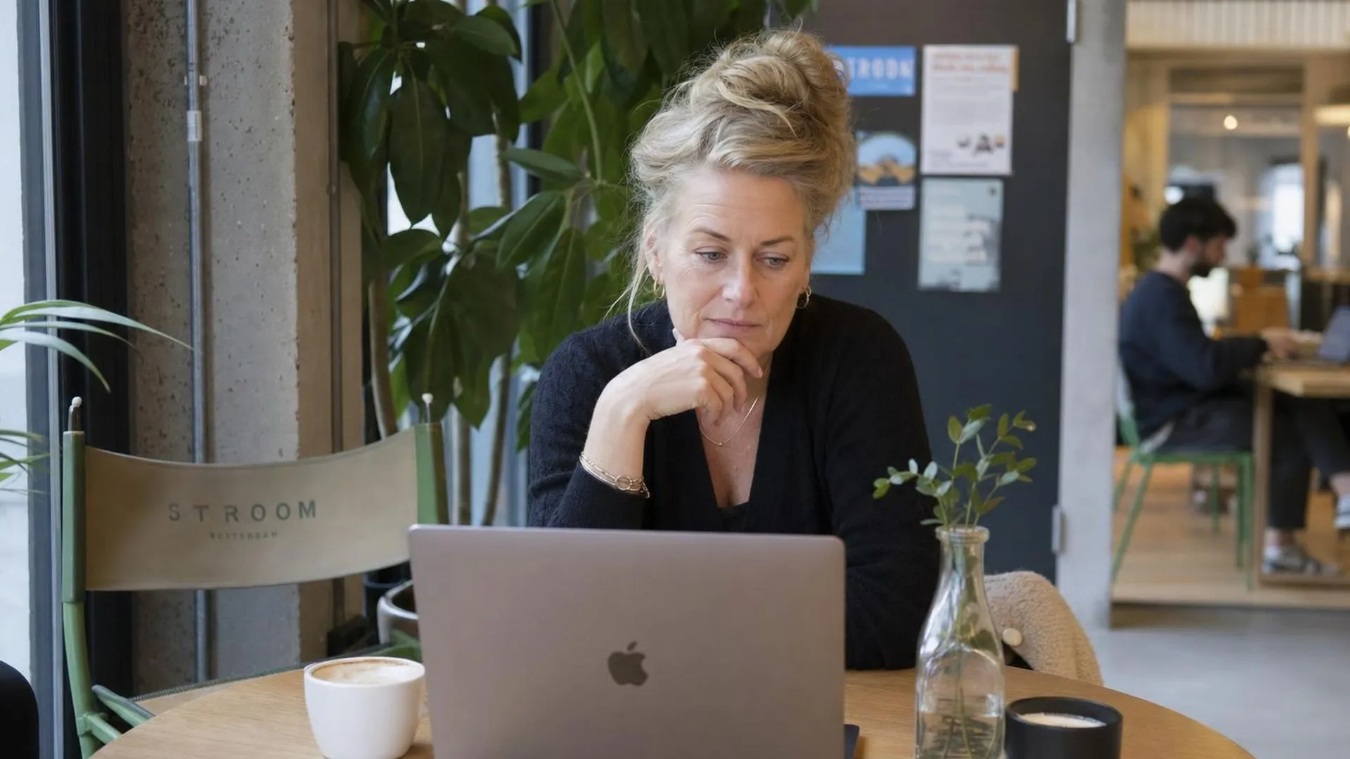 Man zit vermoeid voor zijn laptop in een café zonder te lezen
