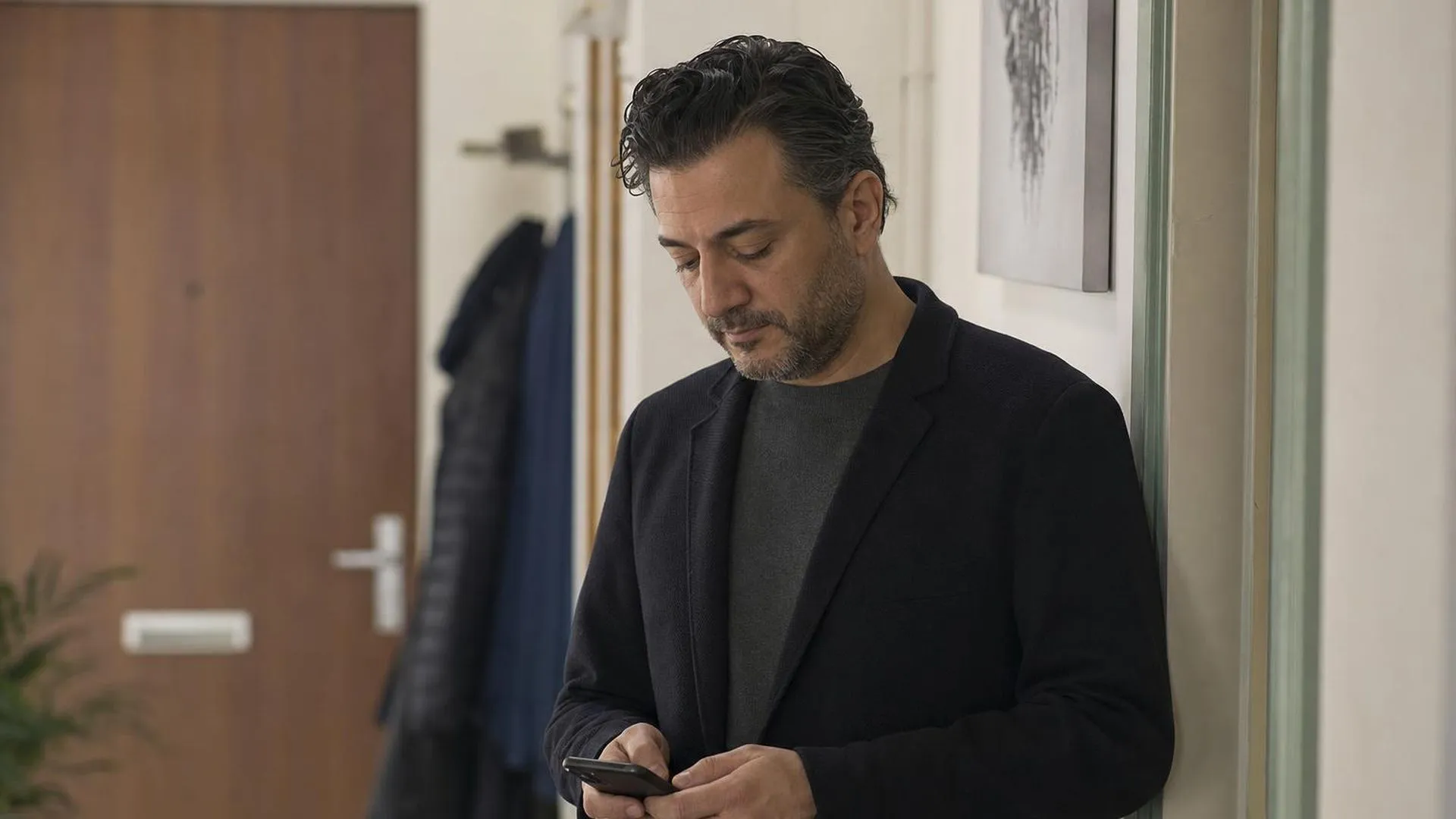 Persoon staat stil in een gang met telefoon in de hand, een moment van aarzeling