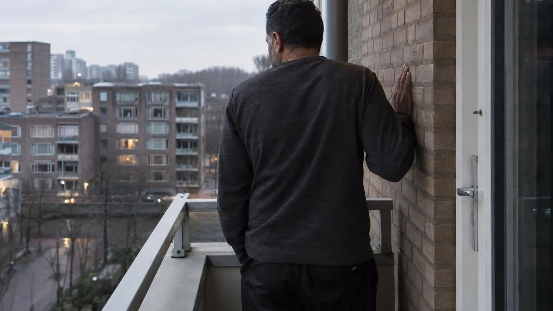 Iemand van achteren, stilstaand in een gang met een hand tegen de muur