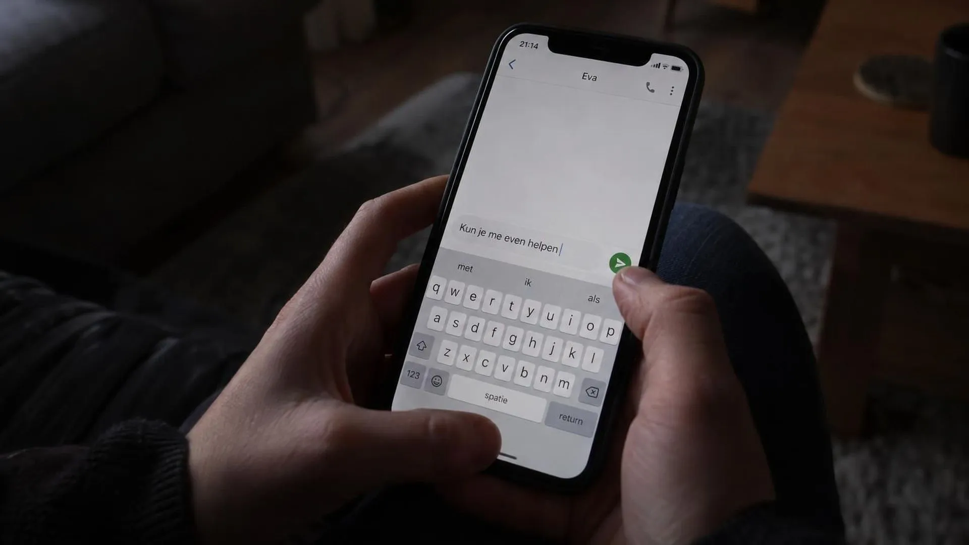Close-up van een hand boven een telefoon met een halfgeschreven berichtje om hulp te vragen.