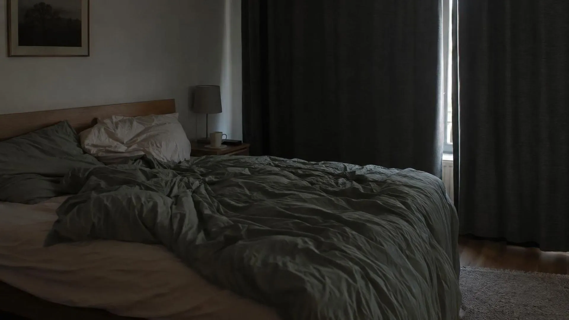 Een bed met dichte gordijnen op klaarlichte dag en een mok op het nachtkastje