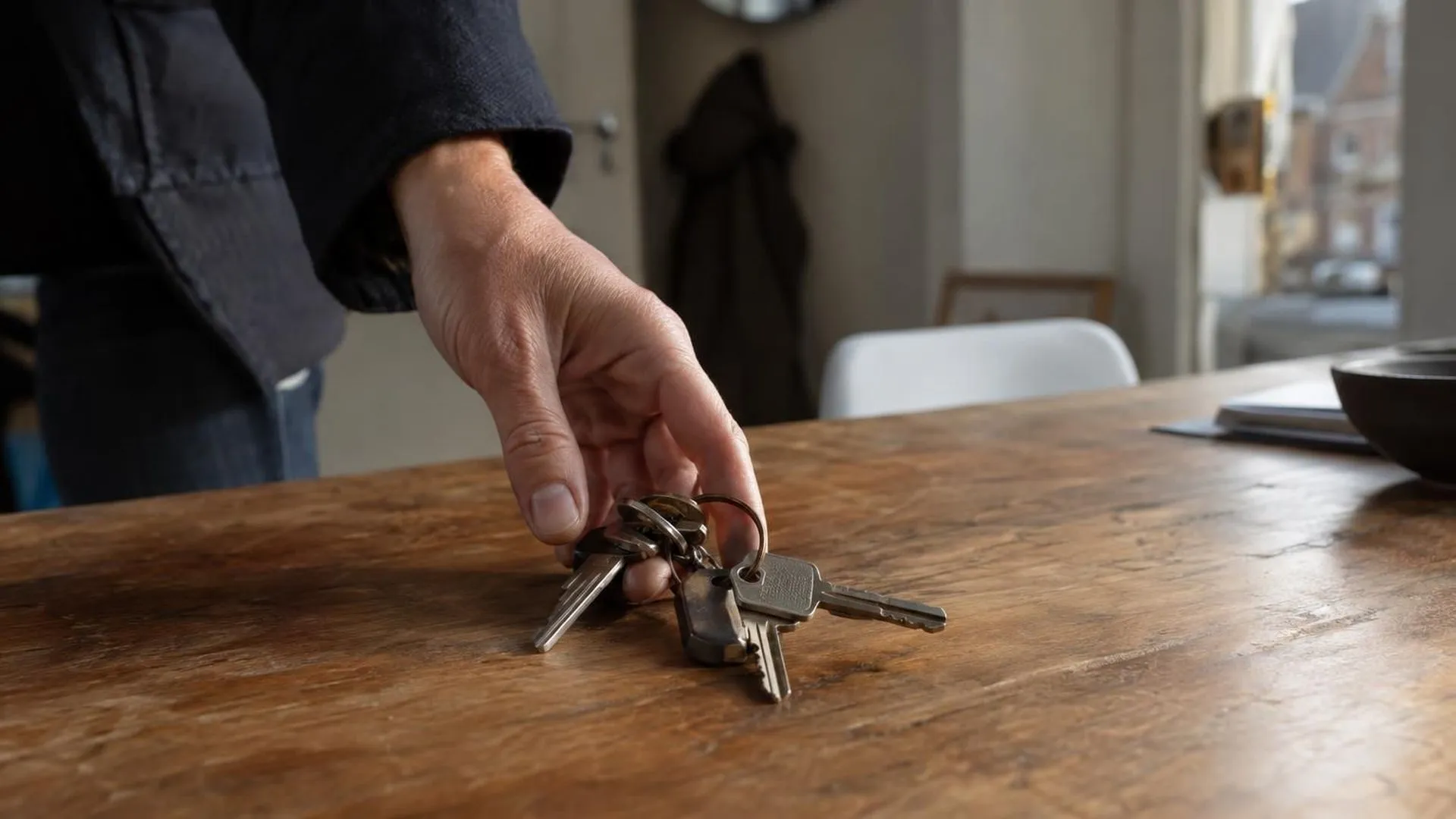 Een hand die zich langzaam opent en een bos sleutels op tafel laat vallen