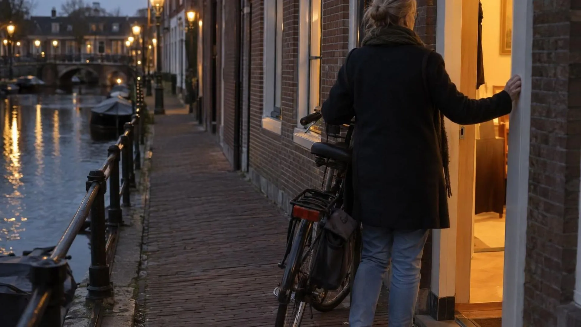 Van achteren gezien aarzelt iemand in een deuropening van een schemerige gang.