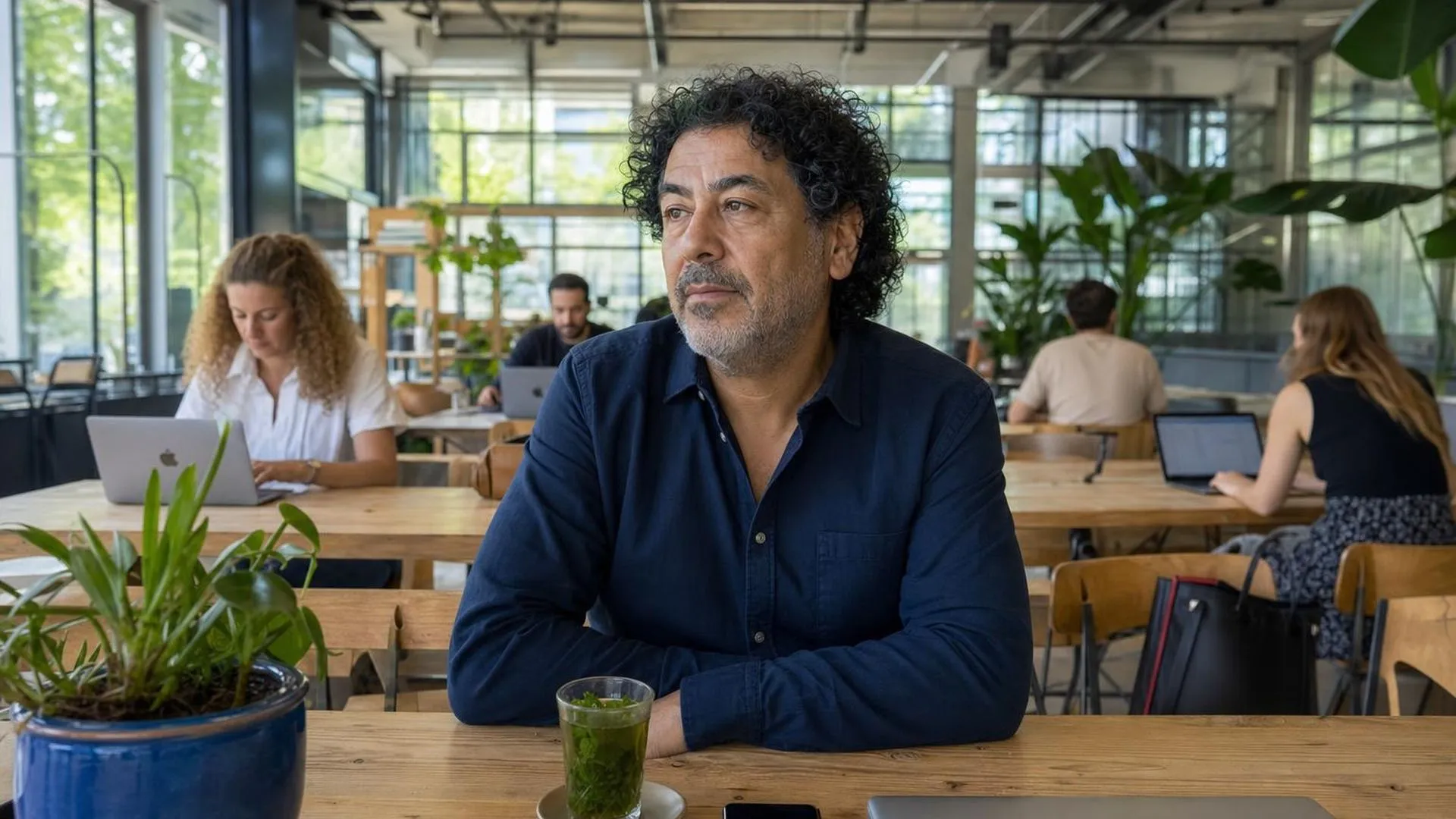 Iemand die in gedachten verzonken zit aan een tafel in een café