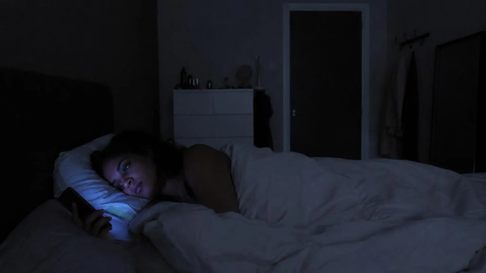 Een donkere slaapkamer om drie uur 's nachts, enkel verlicht door het blauwe schijnsel van een telefoon.