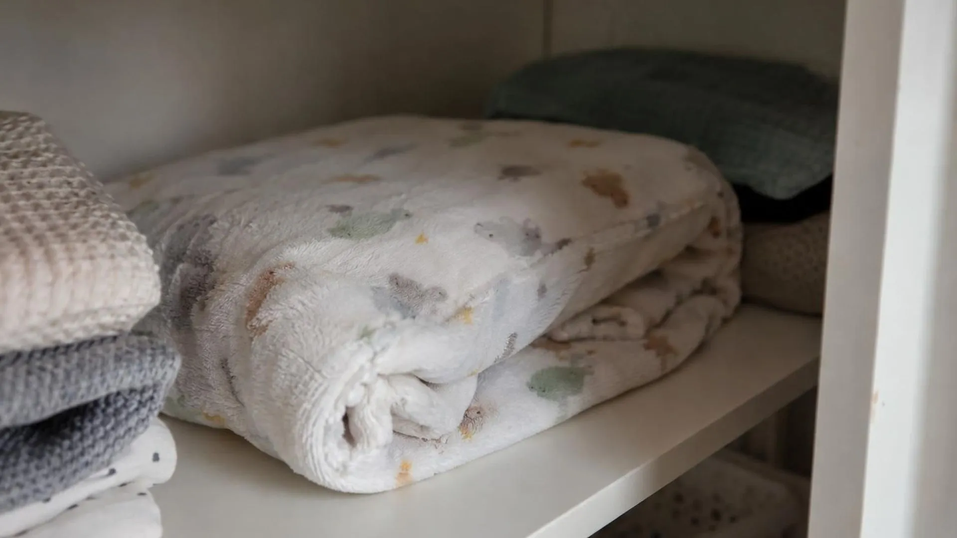 Close-up van een versleten babydekentje, opgevouwen op een plank in de kast