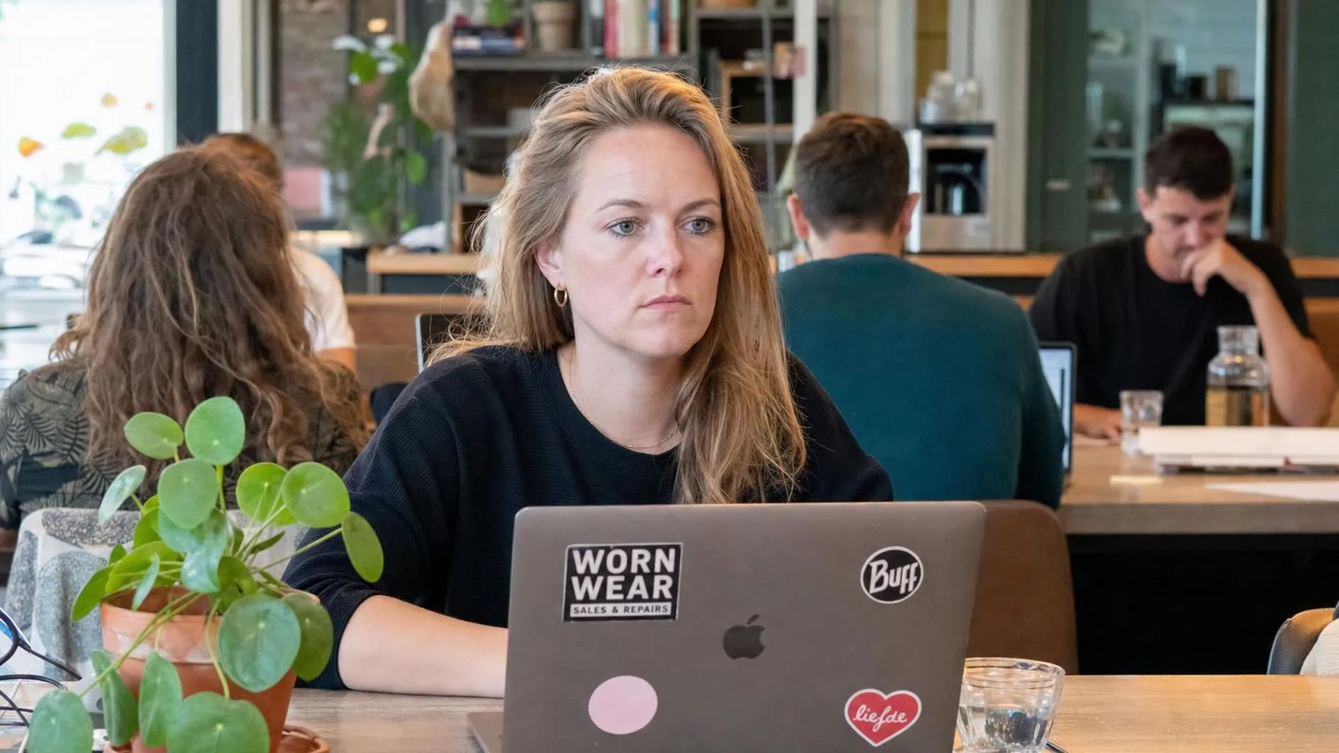 Persoon staart afwezig langs een laptop in een werkruimte
