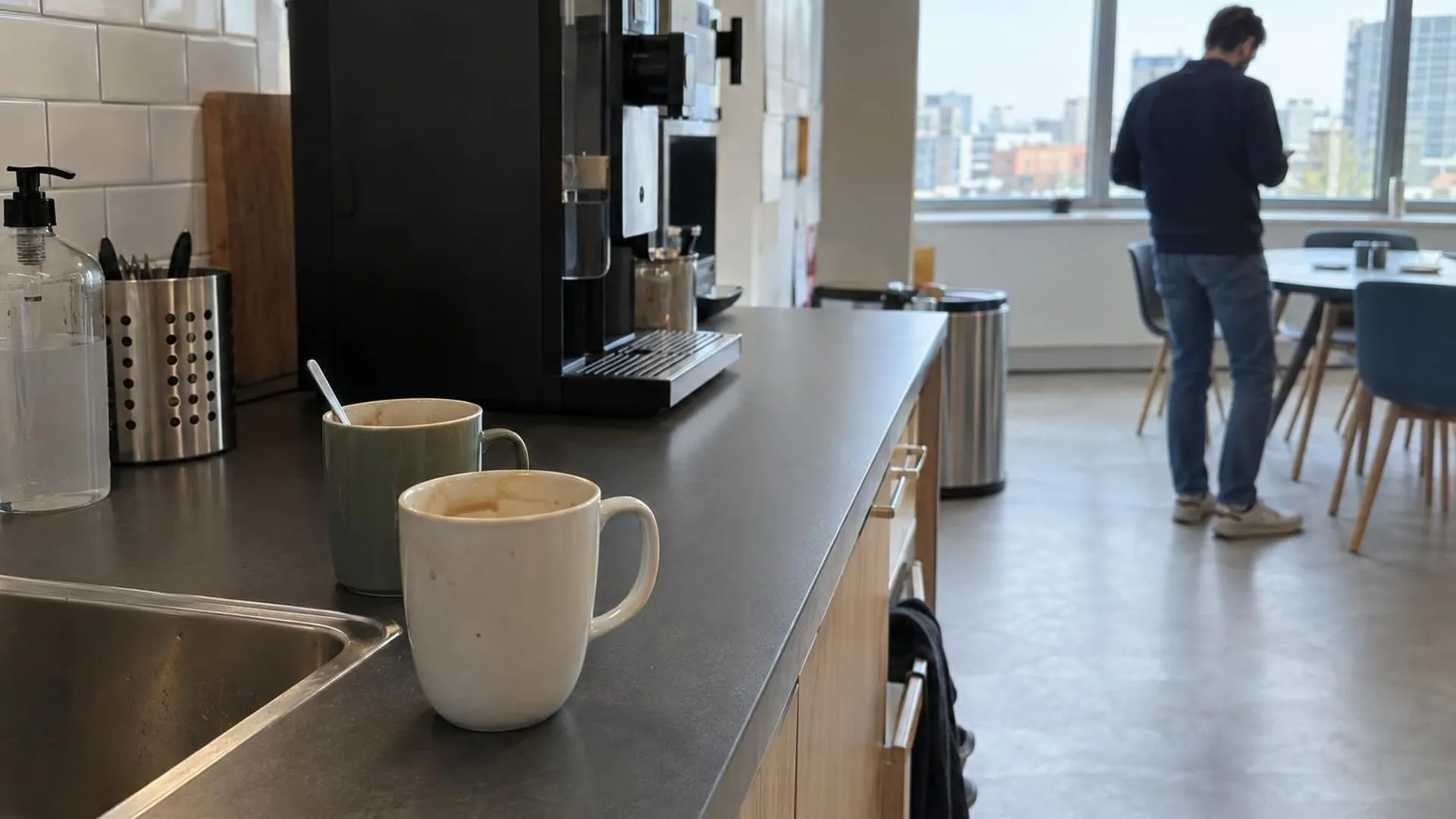 Een kantoorpantry met twee gebruikte koffiemokken, niemand aanwezig.