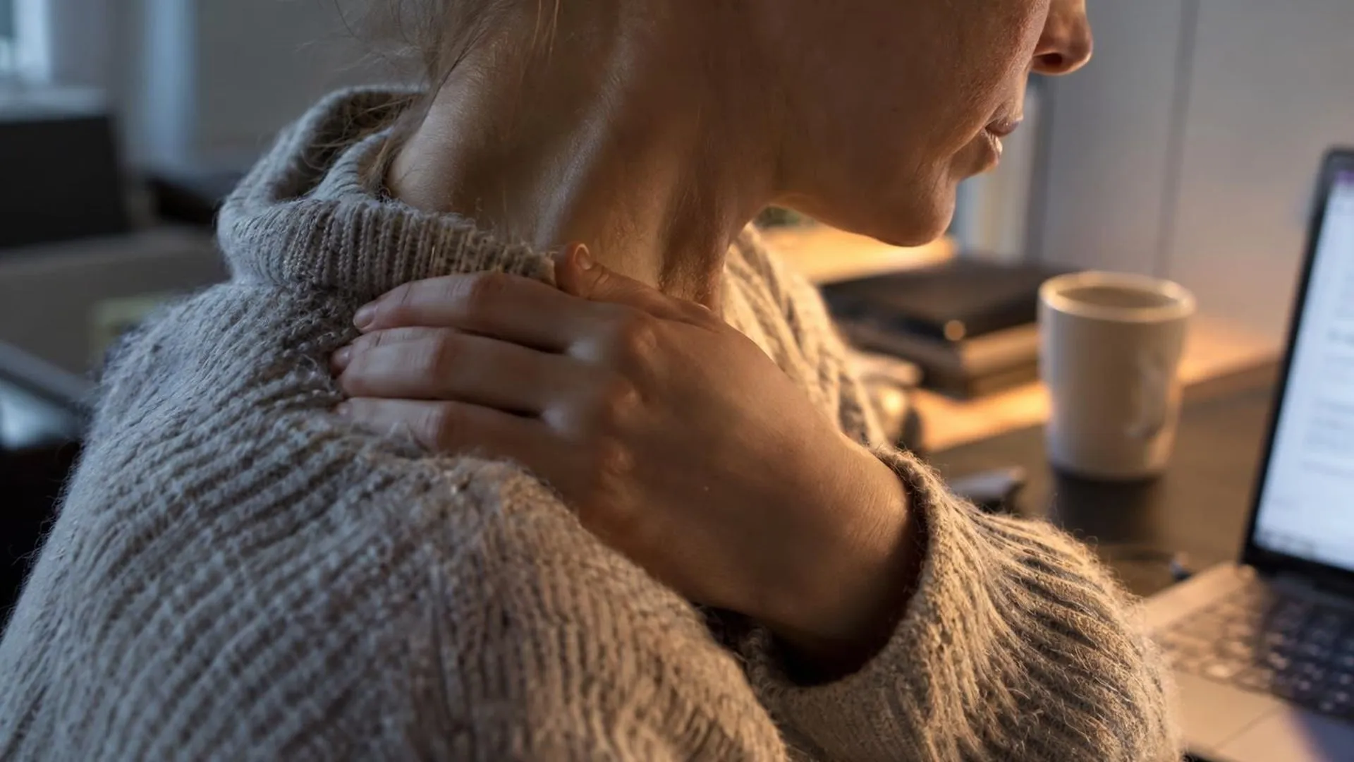 Close-up van een gespannen schouder en nek onder een gekreukelde trui