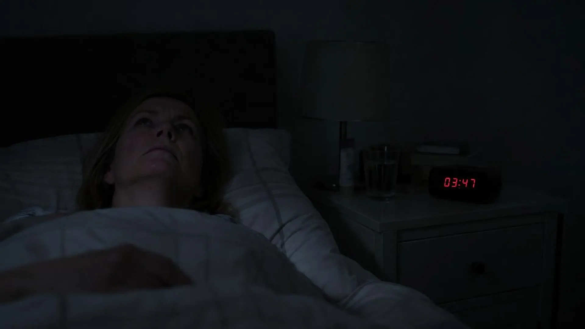 Een wekker geeft 03:47 aan in een verder pikdonkere slaapkamer, het moment waarop iemand wakker ligt te piekeren.