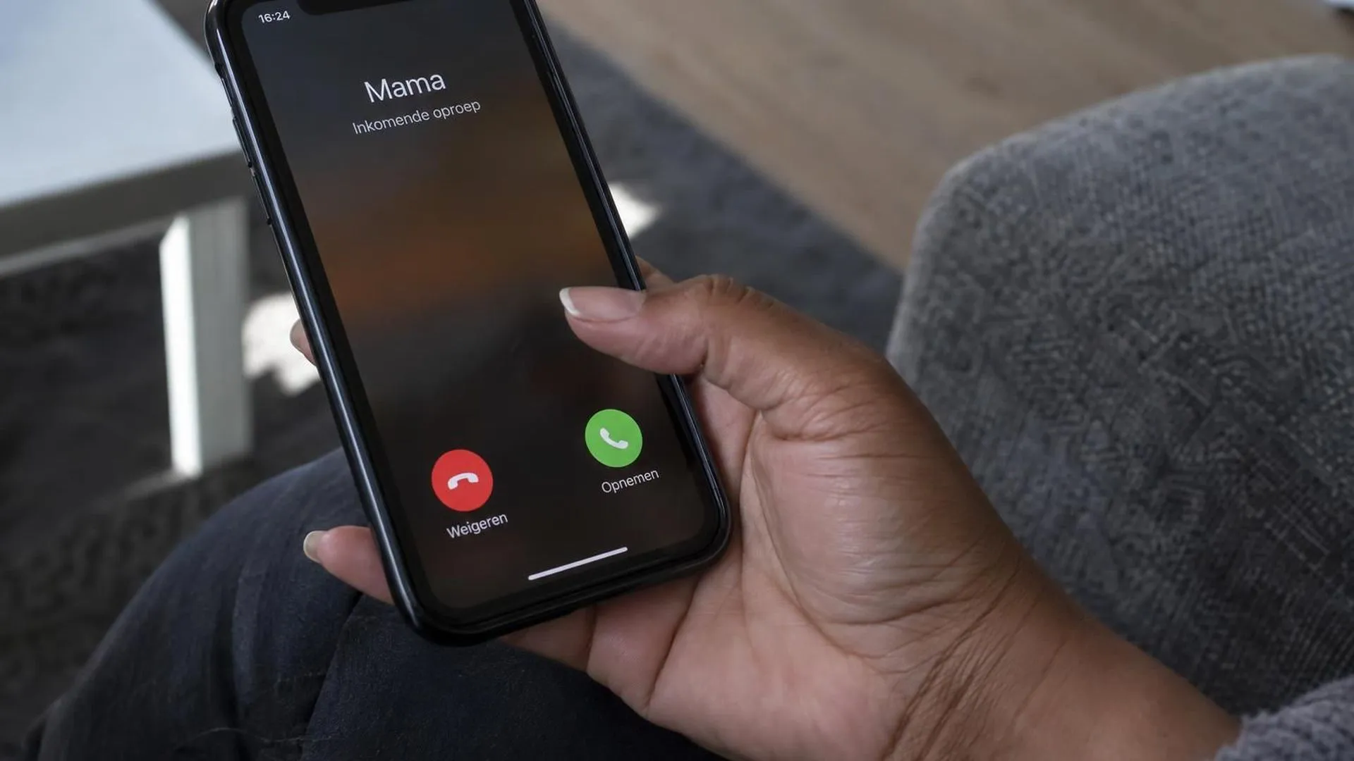 Close-up van een hand met telefoon, duim bevroren boven een binnenkomende oproep die niet wordt opgenomen.