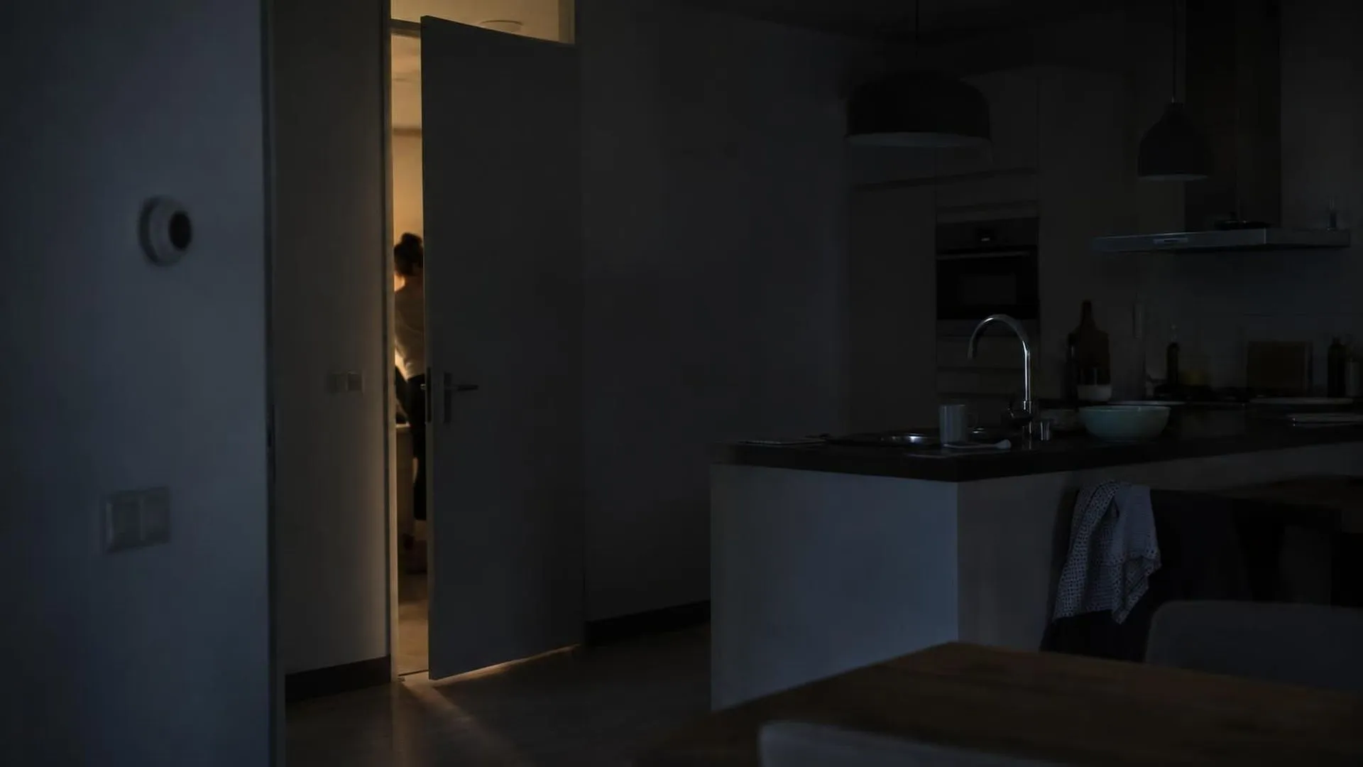 Een figuur nauwelijks zichtbaar door een kier van een bijna gesloten slaapkamerdeur