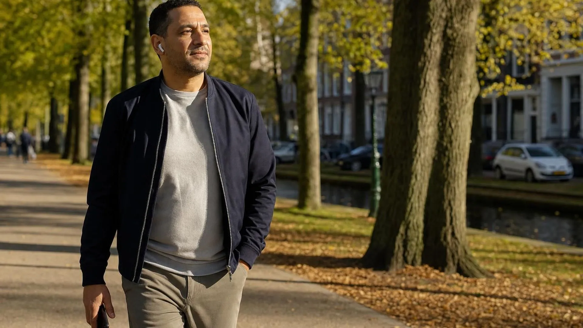 Man wandelt met oortjes in door het park tijdens een online coachgesprek