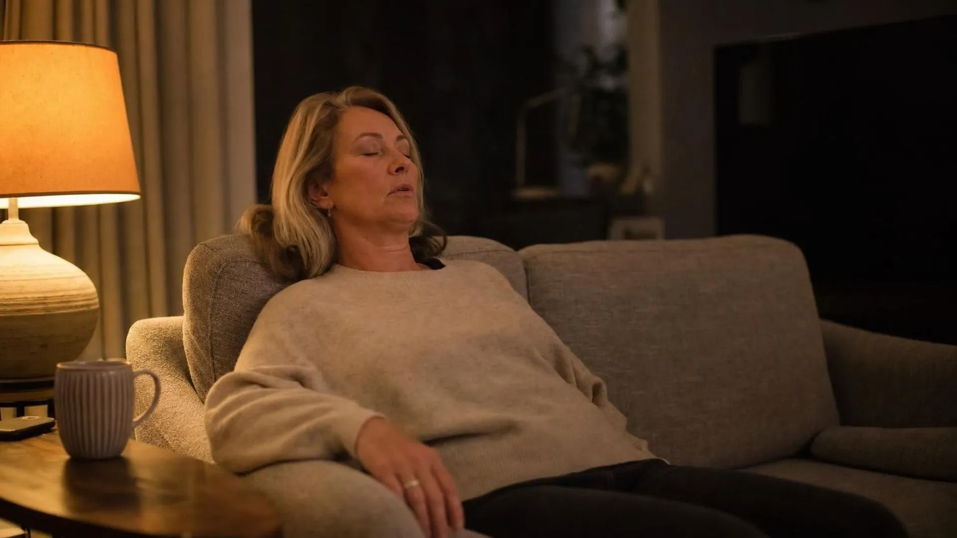 Vrouw op de bank in de avond met een lamp aan