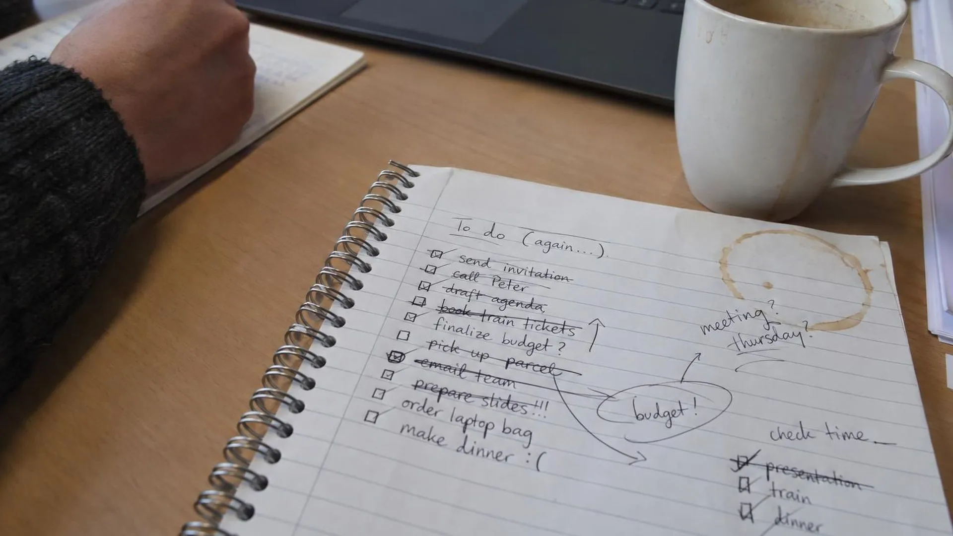 Close-up van een notitieblok vol doorgestreepte en herschreven to-do-lijstjes met een koffievlek in de hoek