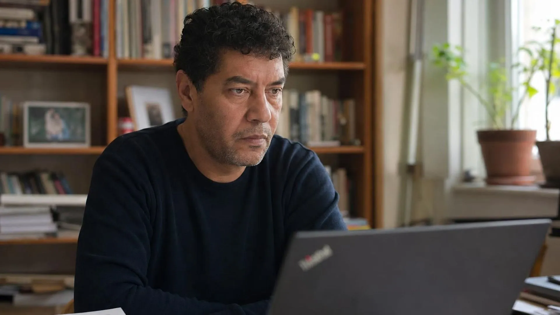 Iemand staart langs het laptopscherm aan een bureau in zacht daglicht