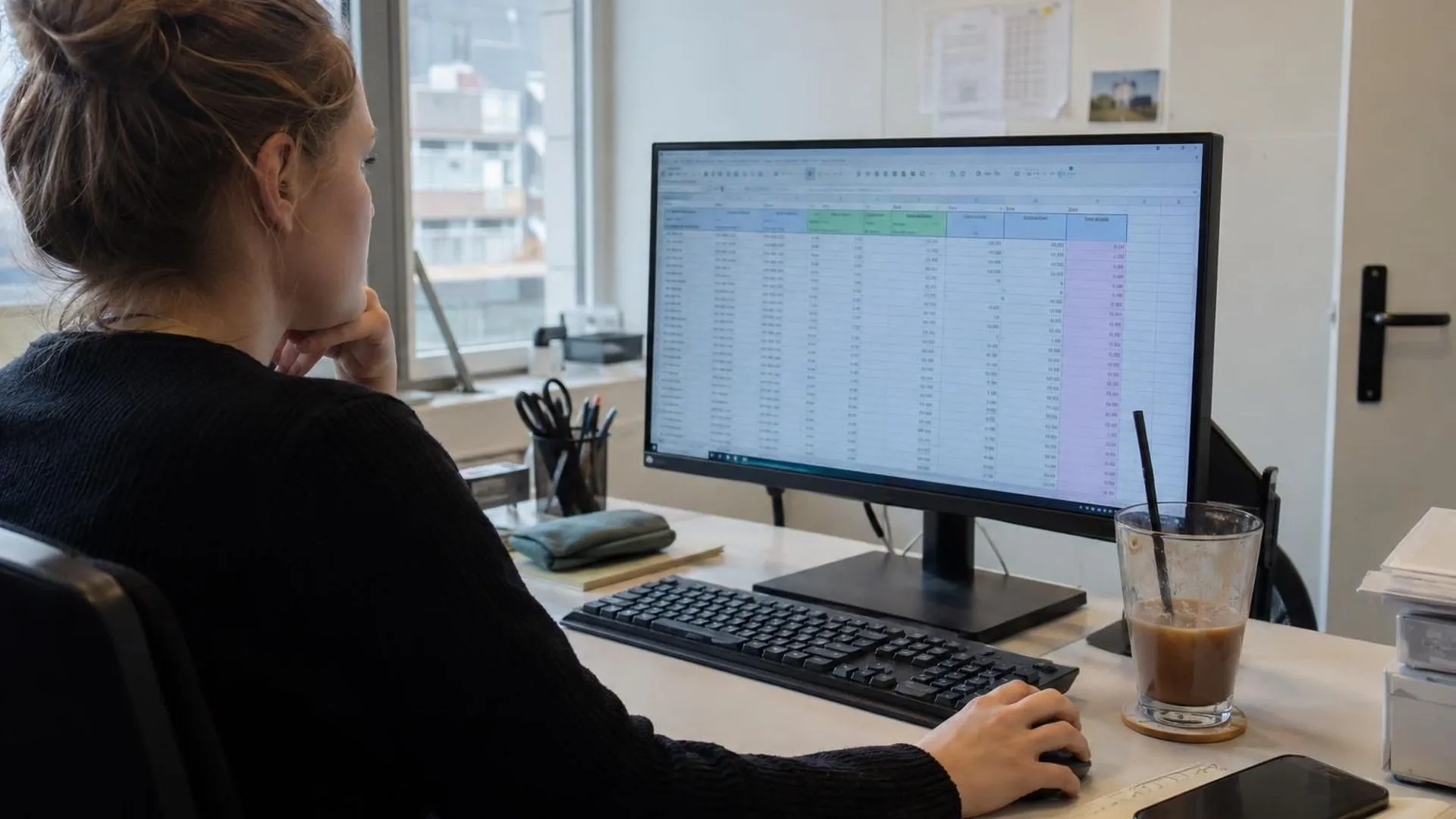 Een bureauscherm met een open Excel-bestand waar de cursor allang niet meer bewogen lijkt, kopje koffie ernaast.