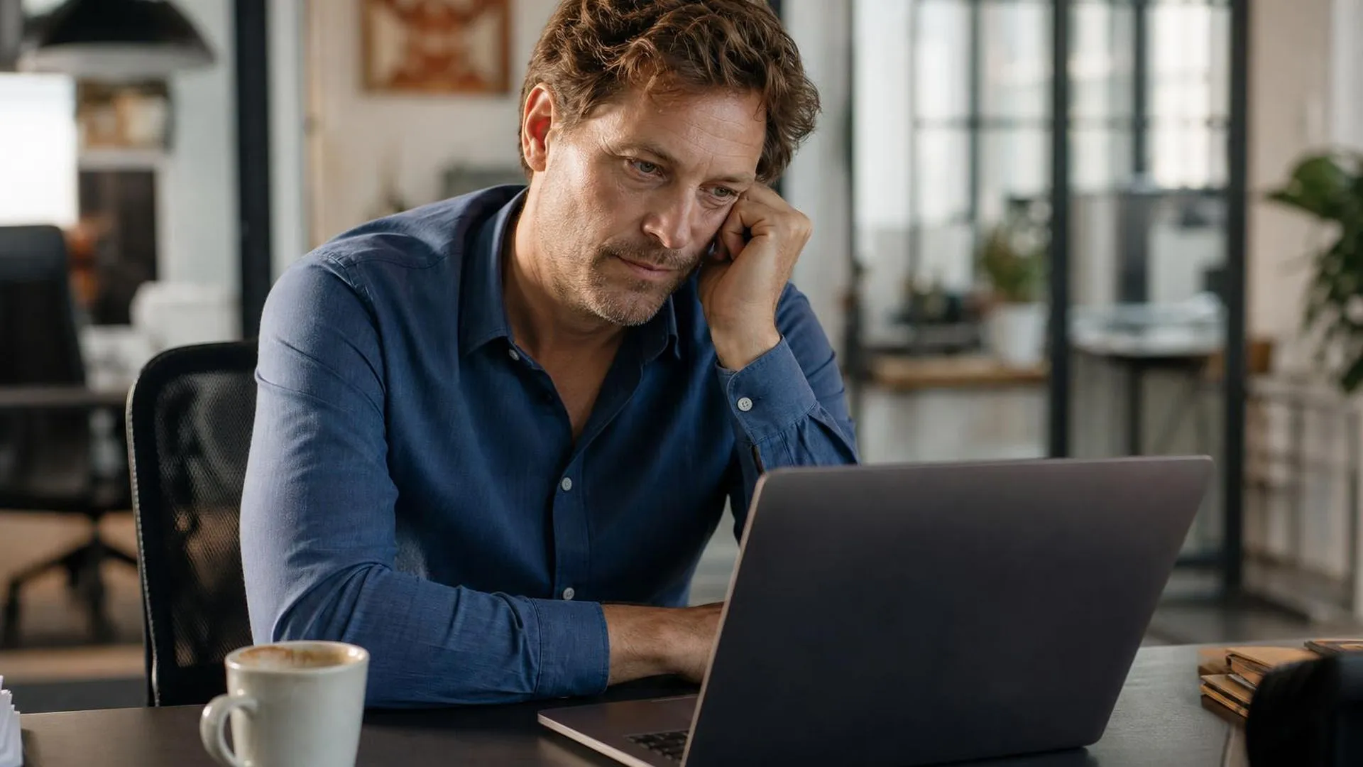 Vermoeide Nederlandse medewerker in zijn veertig achter een laptop in zacht middaglicht, illustratie bij oplopende werkstress en stille stresssignalen op de werkvloer
